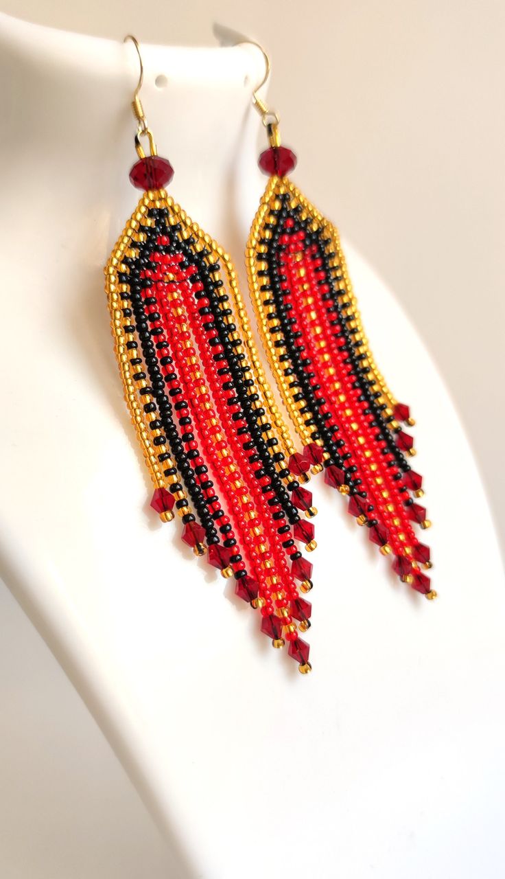 red, black and gold beaded earrings on a white mannequin headdress