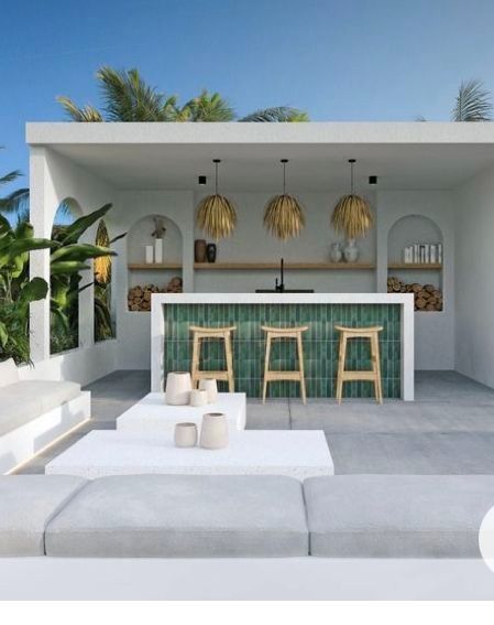 an outdoor living area with white furniture and green tile on the wall, palm trees in the background