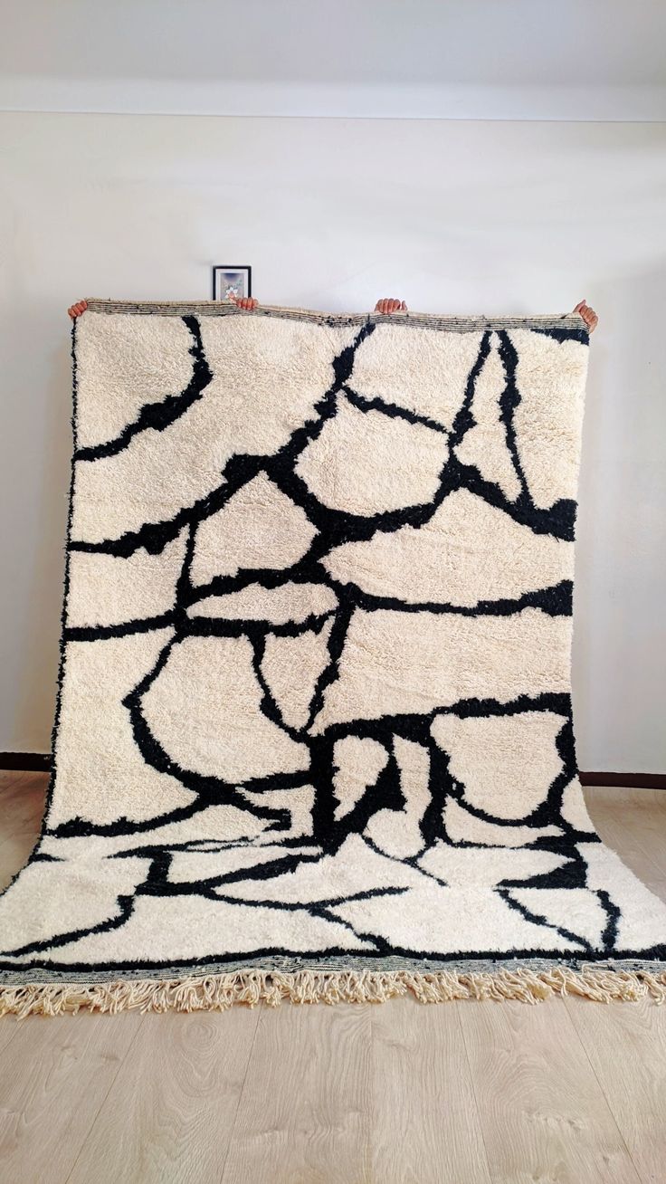 a black and white rug on the floor in front of a wall with a frame