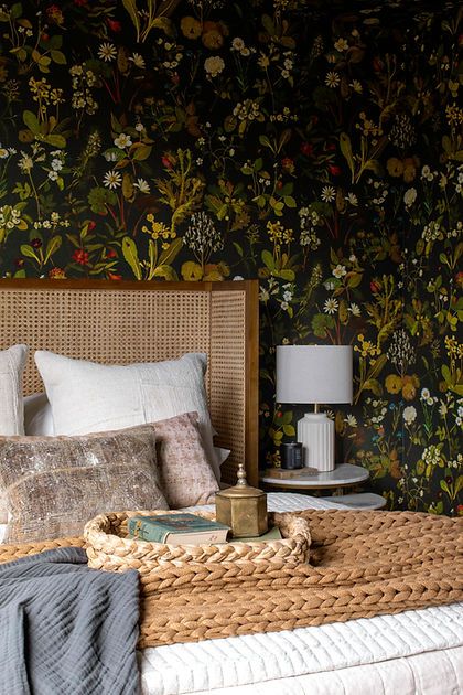 a bedroom with floral wallpaper and wicker headboard on the bed, next to a night stand