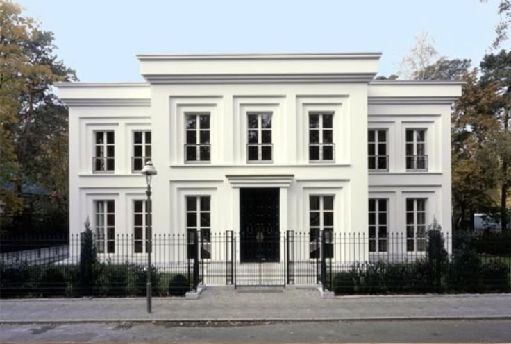 a white two story house with black iron fence around the front door and side entrance