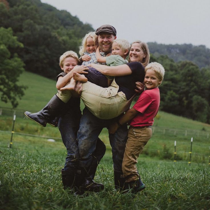 a group of people that are standing in the grass with one person on his back