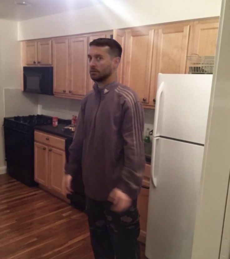 a man standing in a kitchen next to a refrigerator freezer and stove top oven