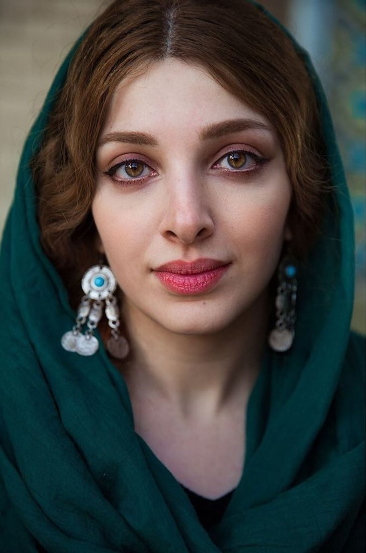 a woman with red hair wearing green scarf and earrings