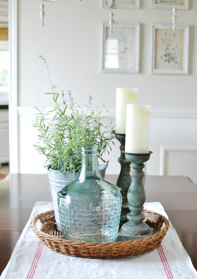 two vases with plants in them sit on a table next to a candle holder