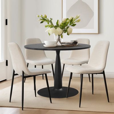 a dining room table with four chairs around it and a vase on top of the table