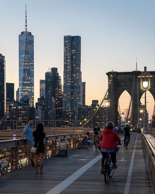 people riding bikes across a bridge in the city