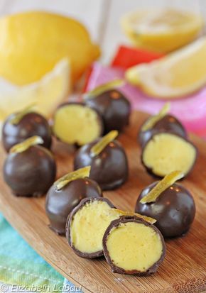 chocolate covered candies are sitting on a cutting board with lemons in the background