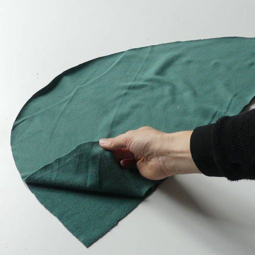 a person holding onto a green cloth on top of a white surface with one hand