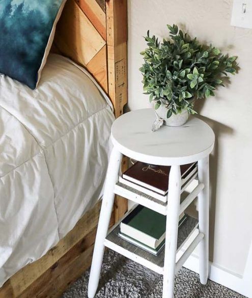 a small white table sitting next to a bed