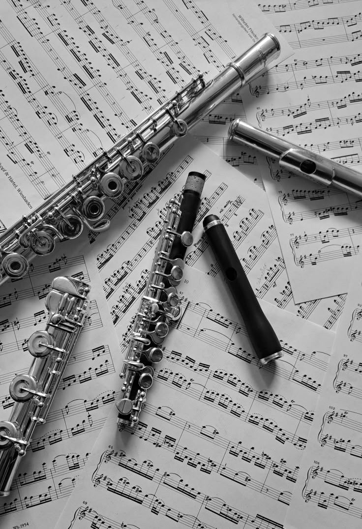 musical instruments on sheet music with pen and recorder in foreground, black and white photograph