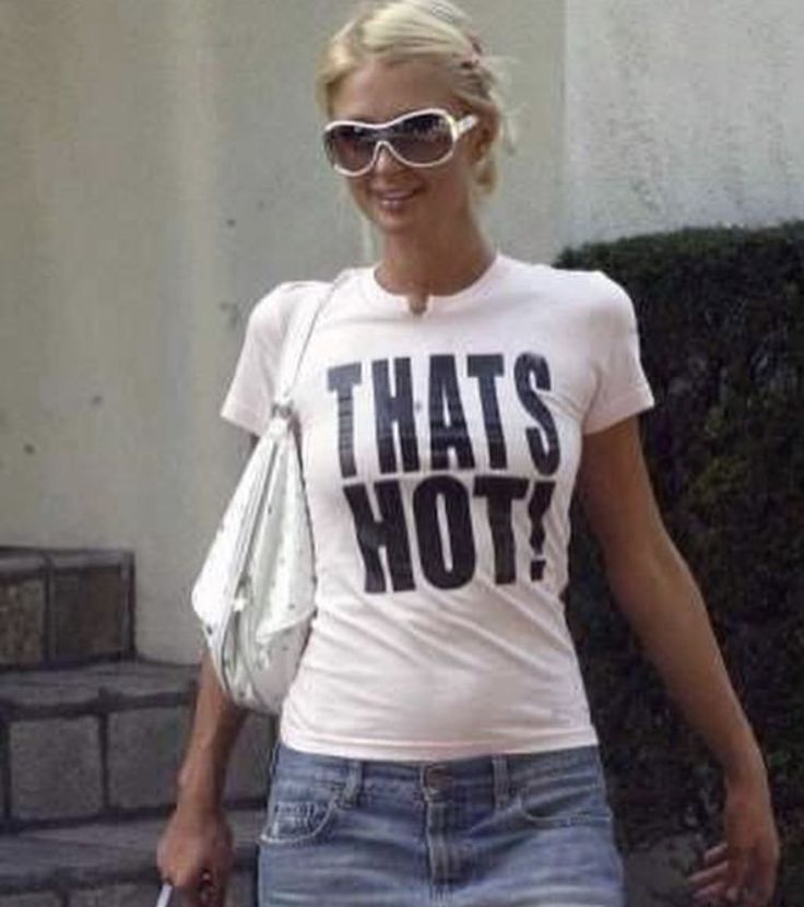 a woman walking down the street with sunglasses on her head and that's hot t - shirt