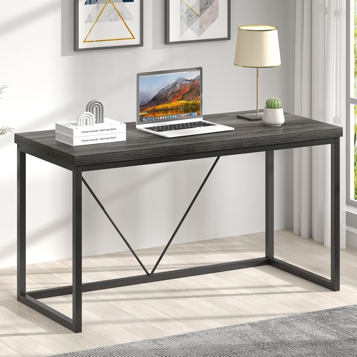 a laptop computer sitting on top of a wooden desk next to a lamp and pictures