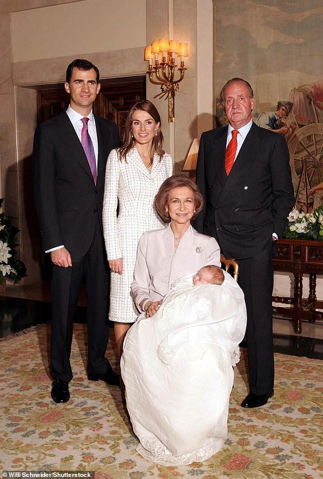 a group of people in suits and ties posing for a photo with a baby on a chair