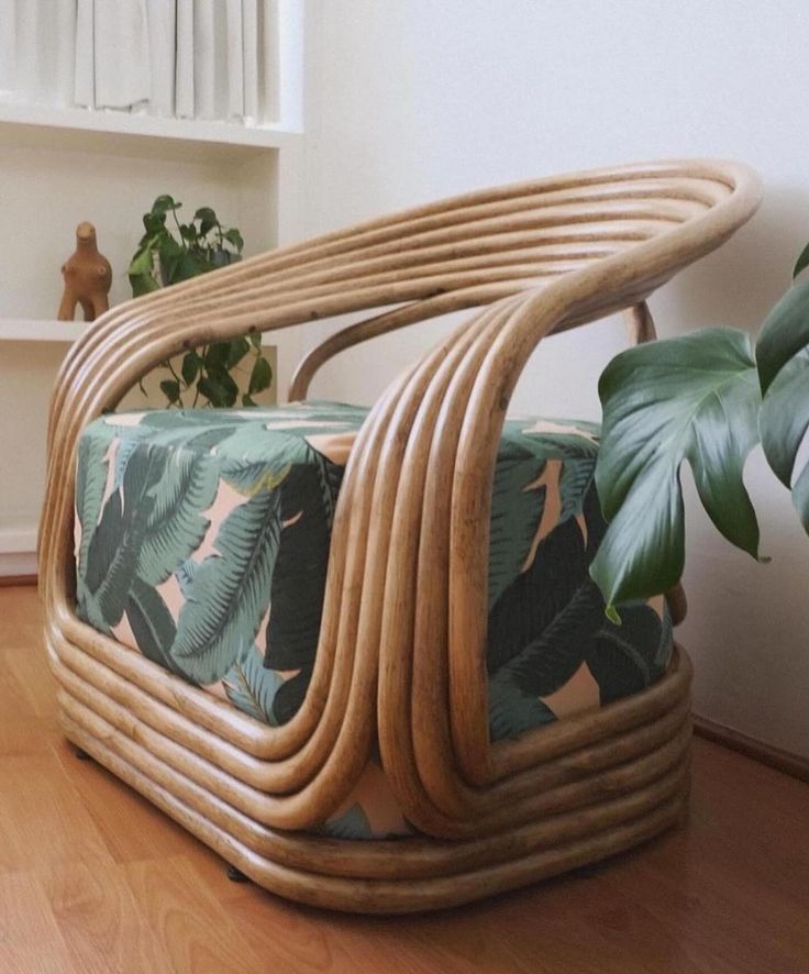 a chair made out of wicker sitting on top of a hard wood floor next to a potted plant