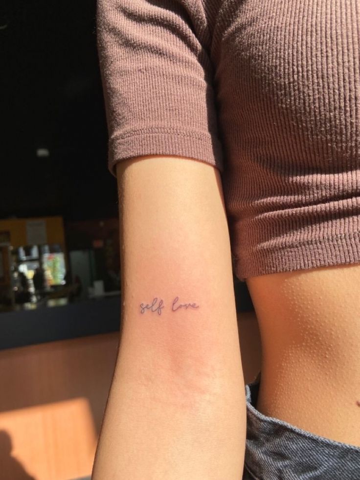 a woman with a small tattoo on her arm that says, my love in cursive writing