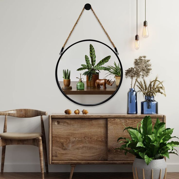 a round mirror hanging on the wall above a wooden dresser with plants and potted plants