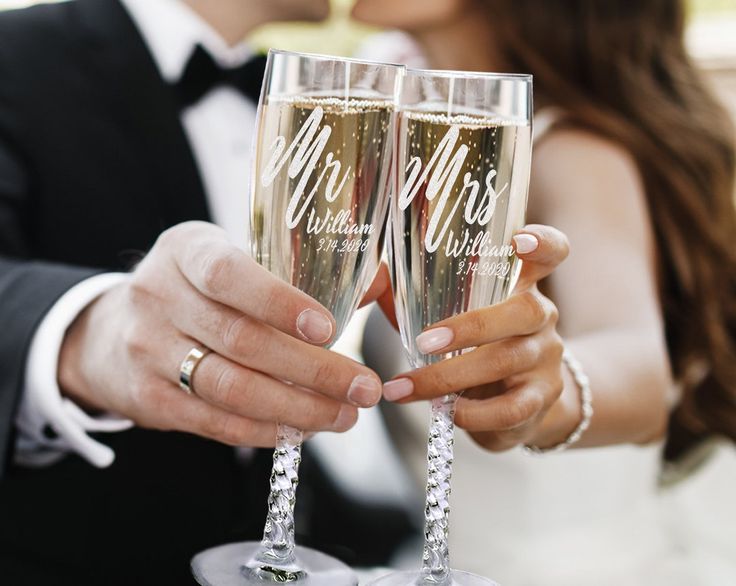 a bride and groom holding champagne flutes in their hands with the bride's name written on them