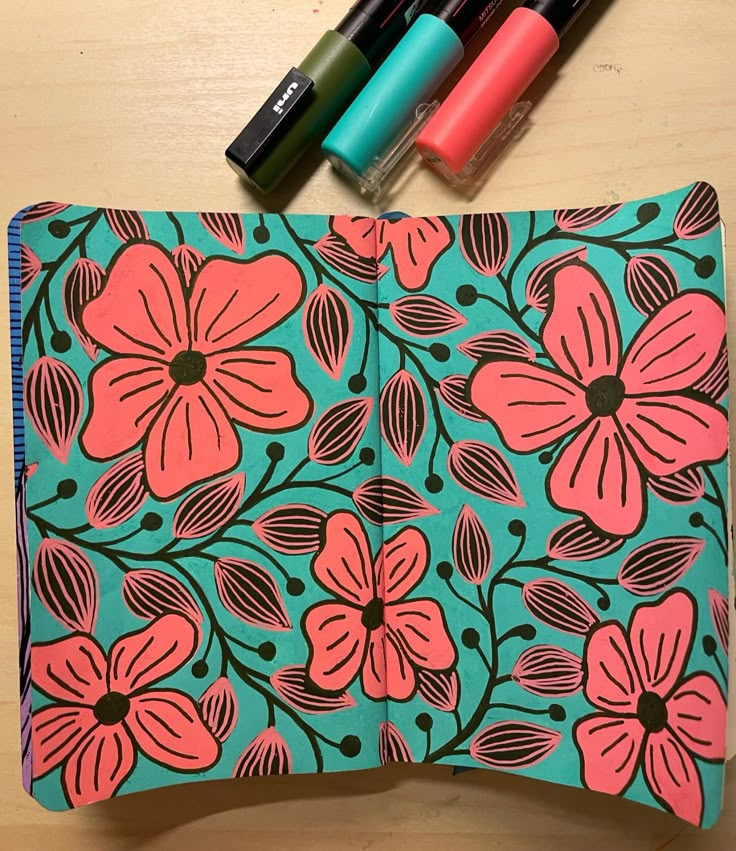 an open notebook with markers and pens on it