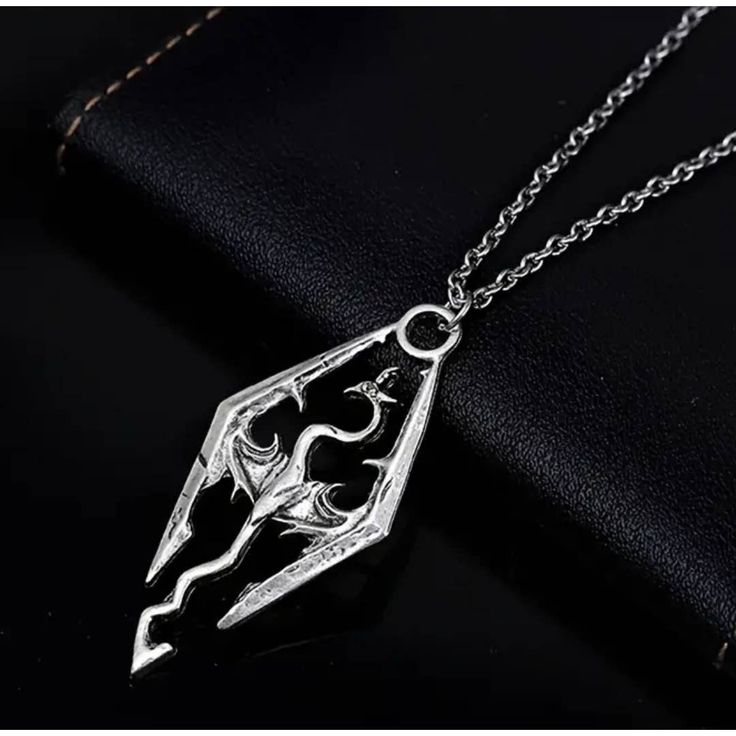 a silver necklace with an image of a person holding a knife in the shape of a heart