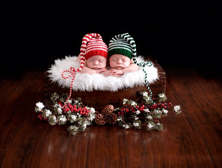 two babies are sleeping in a wooden crate with christmas decorations on the floor and pine cones