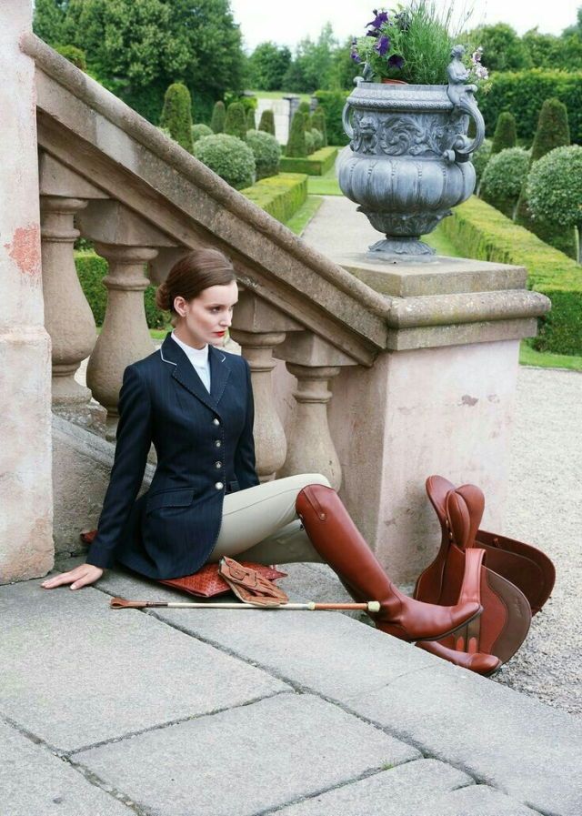 a woman is sitting on the ground with her boots in front of an iron railing