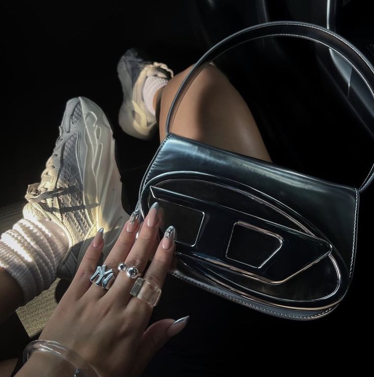 Woman with chrome nails holding a chrome diesel bag Diesel Bag Outfit, Diesel Purse, Diesel Fashion, Diesel Bag, Y2k Bags, Diesel Clothing, Silver Bags, Fancy Bags, Bags Aesthetic