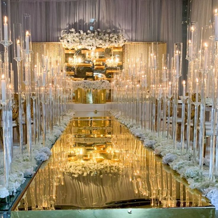 a long table with candles and flowers on it in the middle of a room filled with chairs