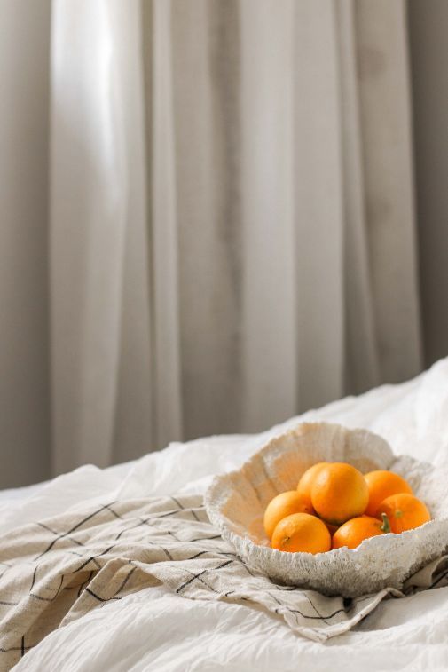 a bowl filled with oranges sitting on top of a bed