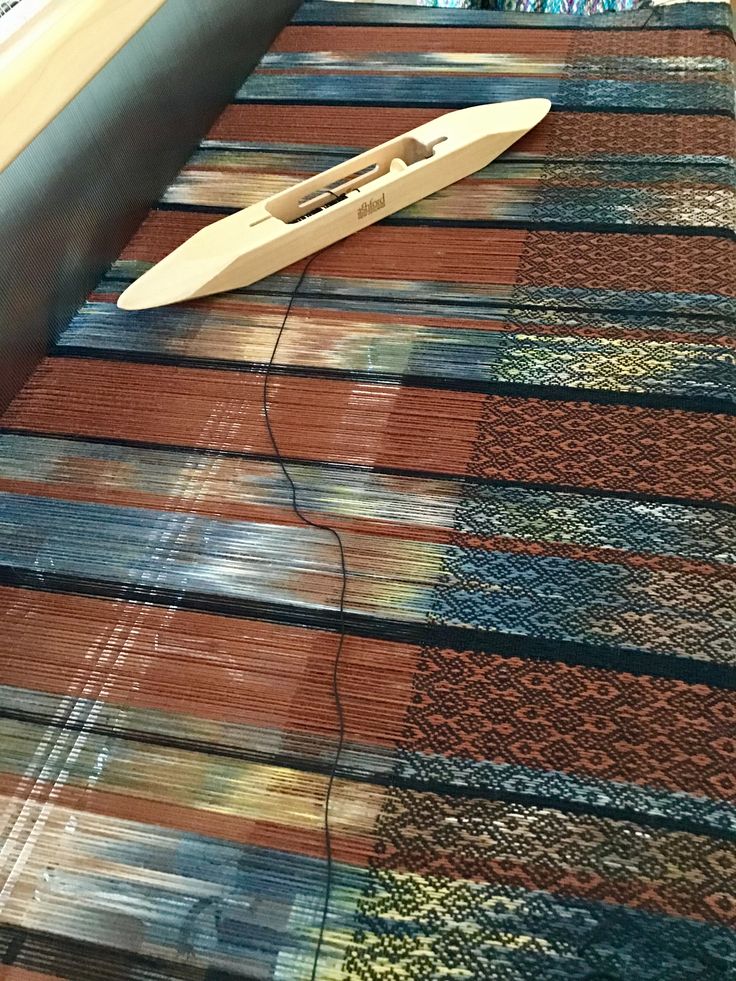 a surfboard laying on top of a colorful rug