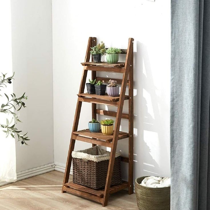 a wooden shelf with plants on it in front of a window next to a potted plant