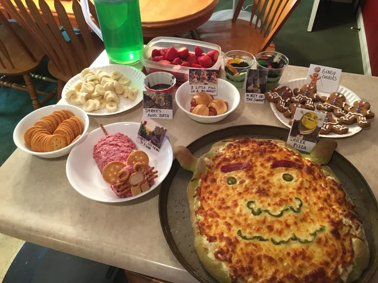 a table topped with plates and bowls filled with food next to a pizza on top of a pan