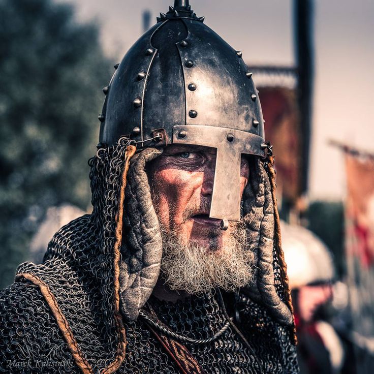 a man wearing a helmet with braids on his head and beard is standing in front of other people