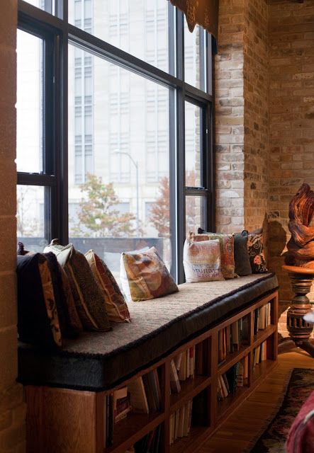 a living room filled with lots of furniture next to a large window covered in pillows