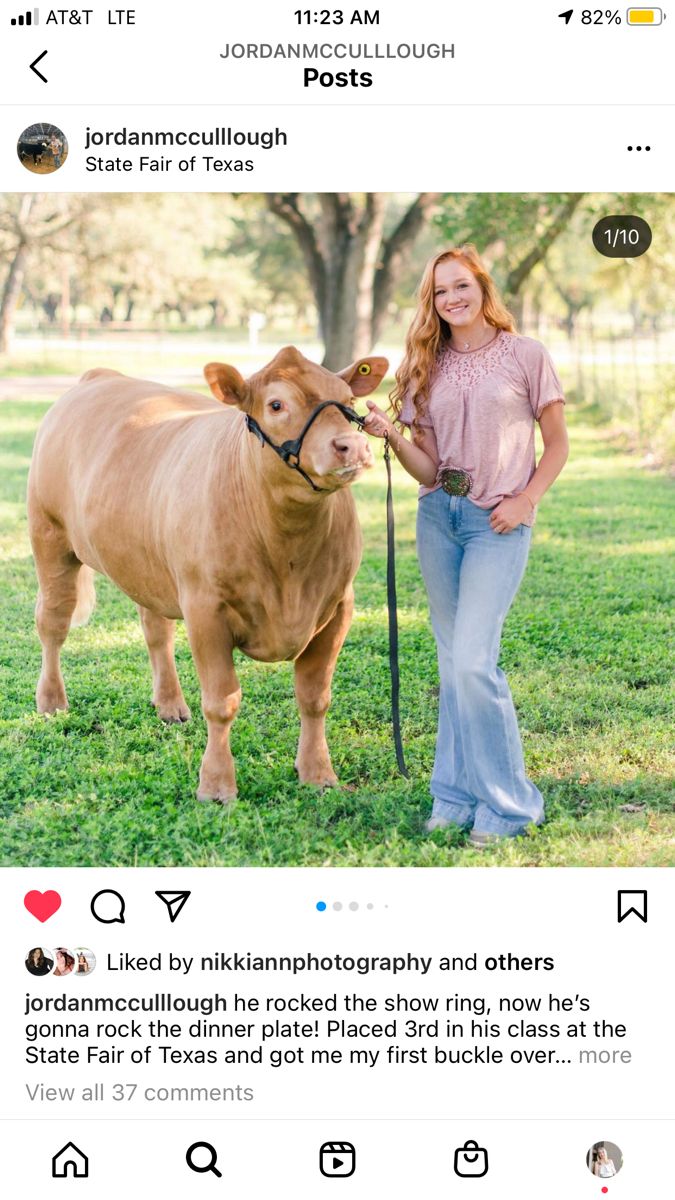 a woman standing next to a brown cow on top of a lush green field