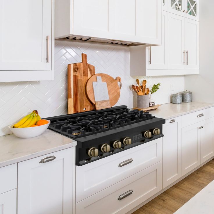 a kitchen with white cabinets and an island in front of the stove top is shown