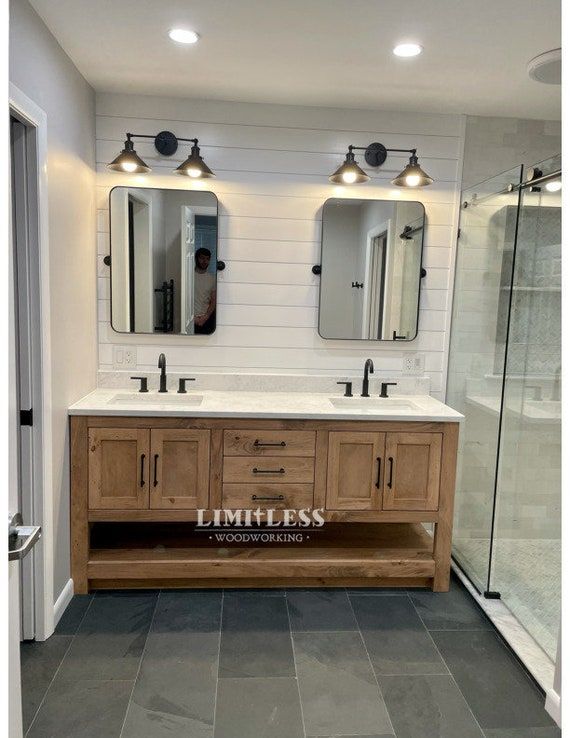 a bathroom with two sinks and mirrors on the wall next to a walk in shower