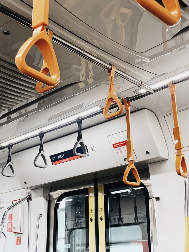 the inside of a subway car with yellow handles and hooks hanging from it's ceiling