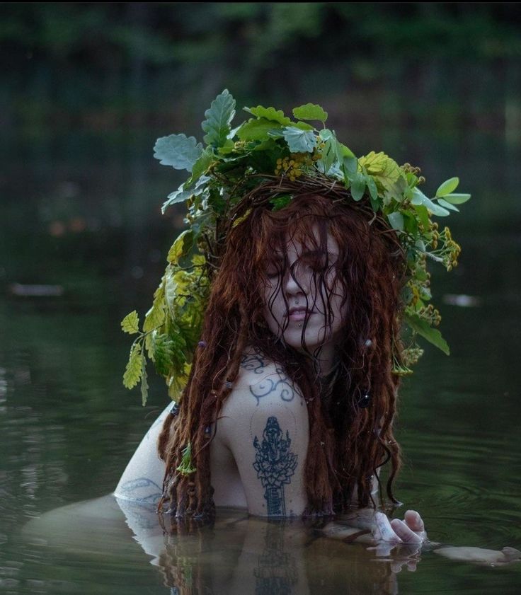 a woman with long red hair is floating in the water wearing a wreath on her head