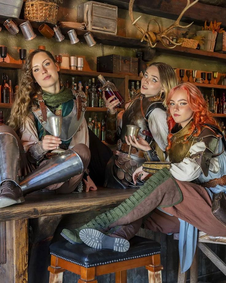 three women dressed in medieval costumes sitting at a bar