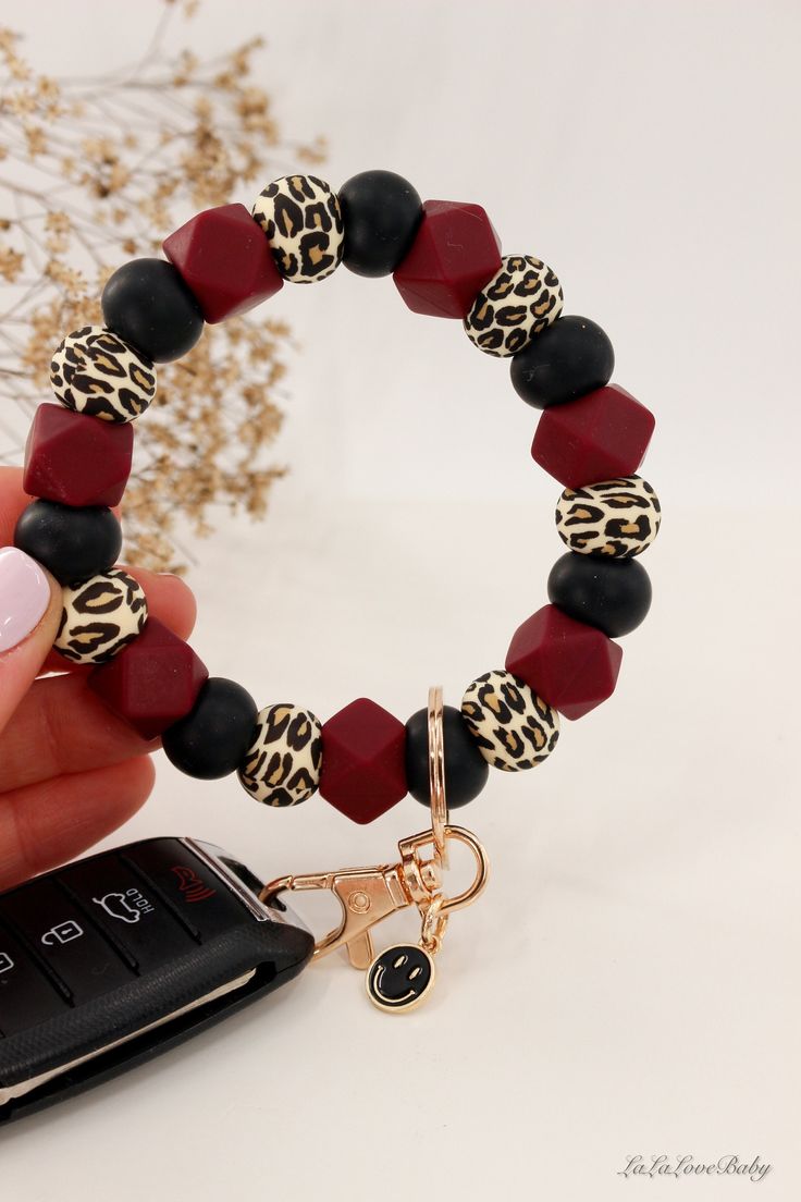 a woman holding onto a cell phone and wearing a bracelet with leopard print beads on it