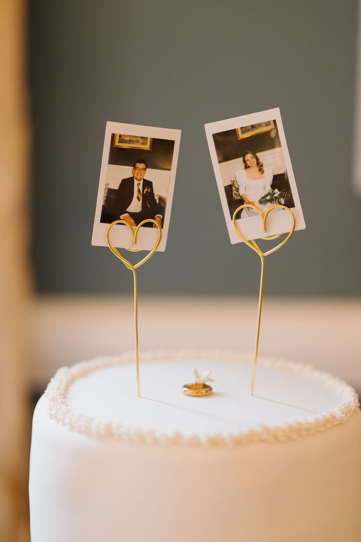 two wedding photos are placed on top of a white cake with gold decorations and hearts