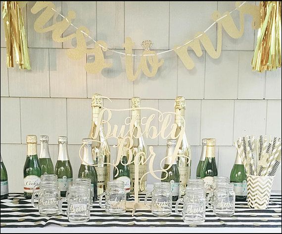 a table topped with lots of bottles and glasses filled with champagne next to a banner