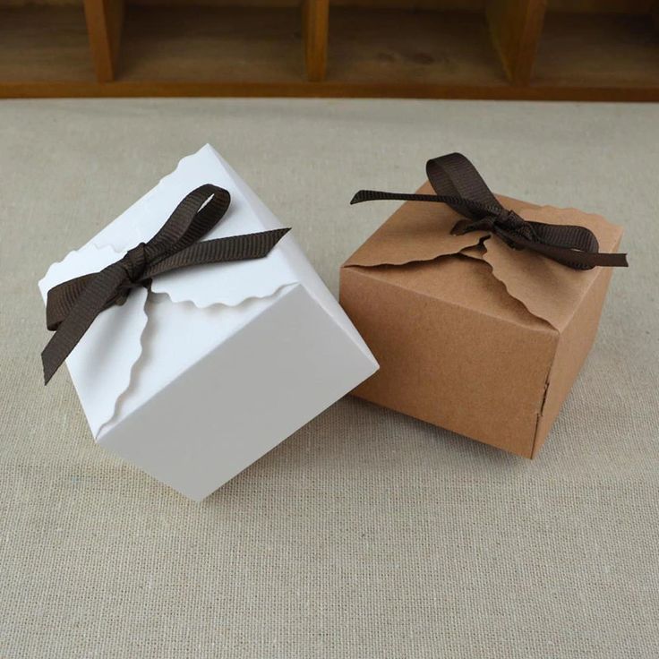 two white boxes with black bows are sitting on the floor