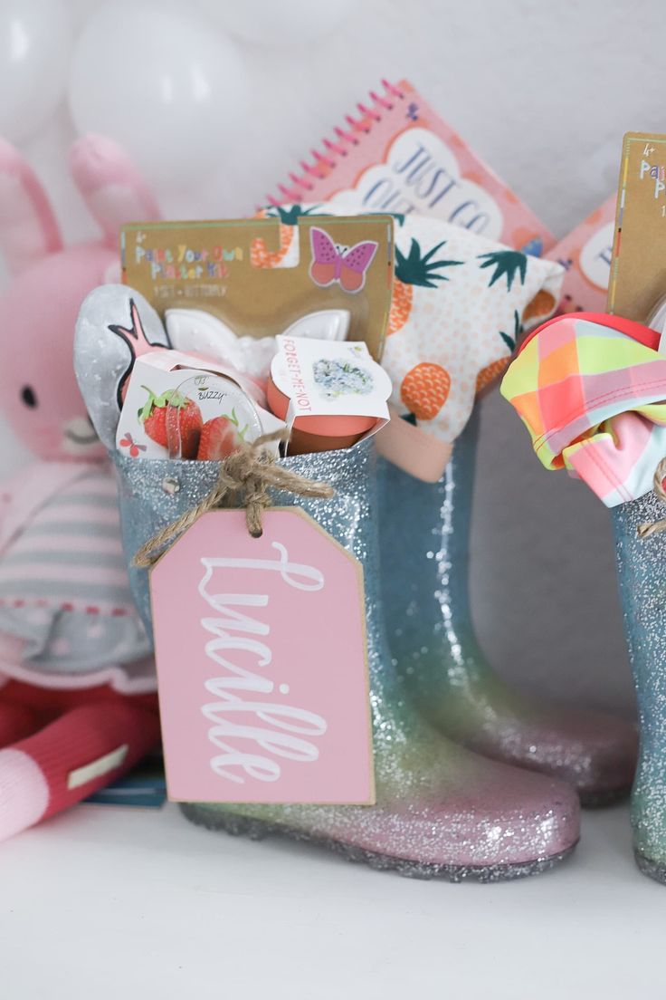 a pair of blue rubber boots with tags attached to them sitting next to a pink teddy bear