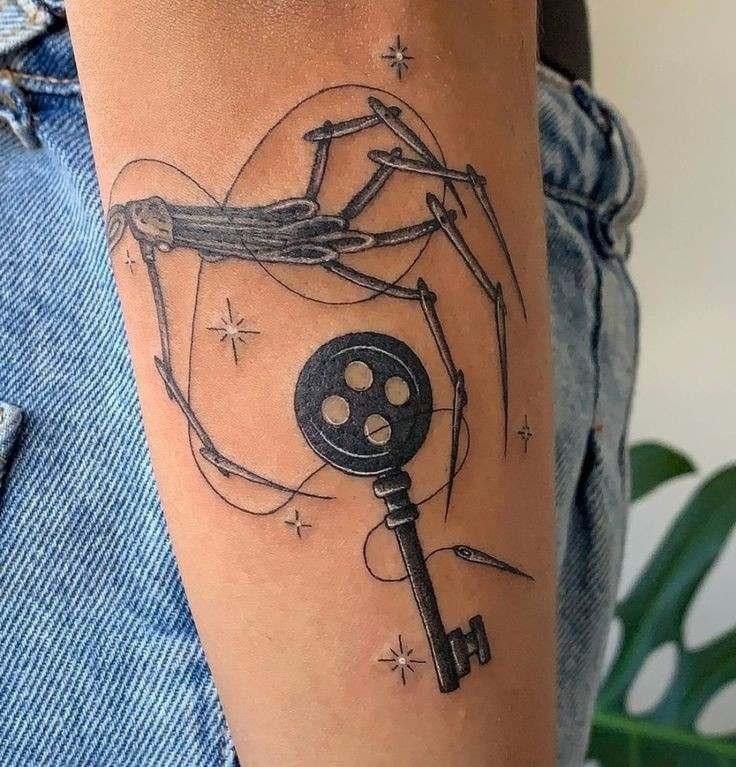 a tattoo on the arm of a person with a key in it and a spider