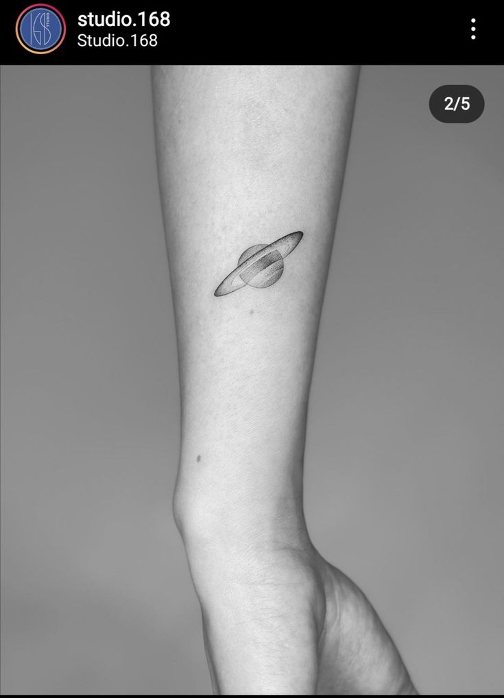 a black and white photo of a person's leg with a saturn tattoo on it