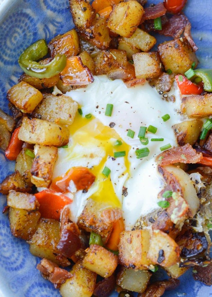 a blue and white bowl filled with potatoes, eggs and peppers on top of it