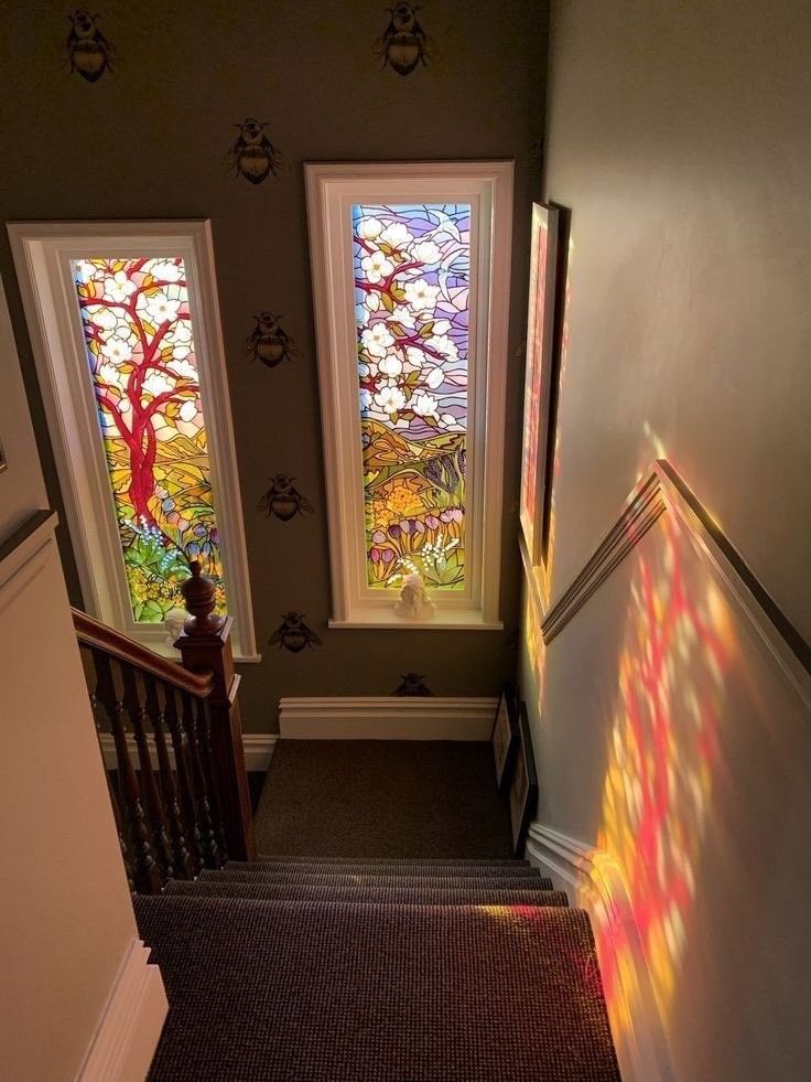 two stained glass windows on the side of a staircase leading up to a second floor