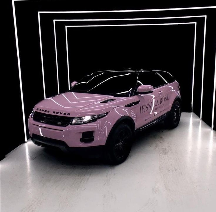 a pink car is parked in front of a black and white wall with lines on it